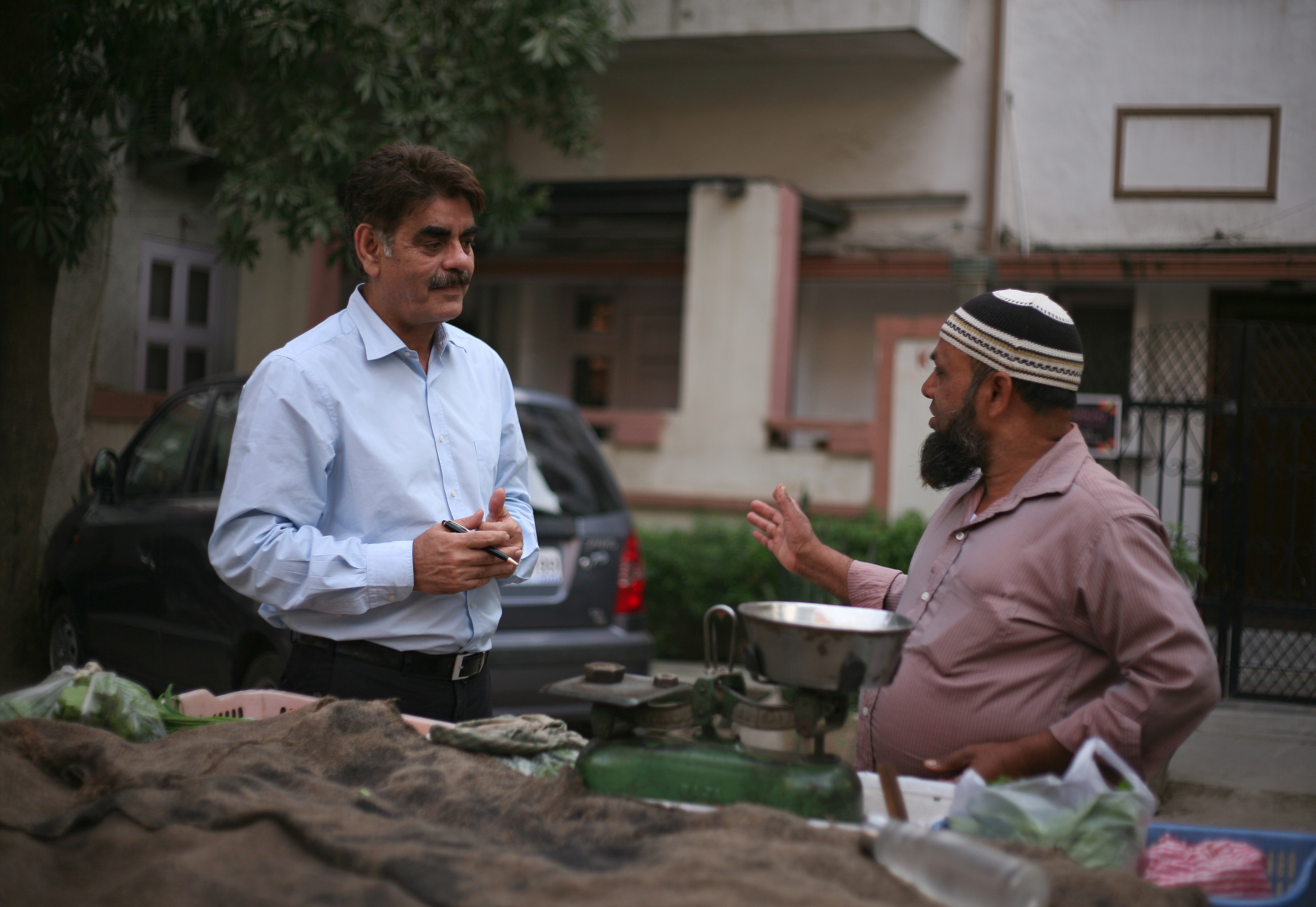 Mohammad Saqib (left) talks to a vegetable vendor.