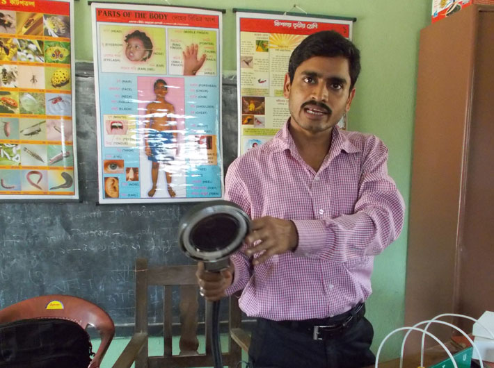 Special educator Rajkumar Bhuniya demonstrates the use of a lamp for low vision, but which cannot be used due to absence of electricity.
