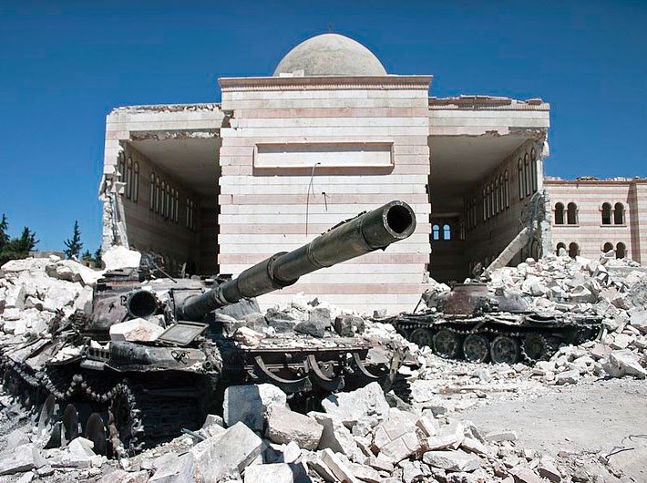 Two destroyed tanks in front of a mosque in Syria in 2012