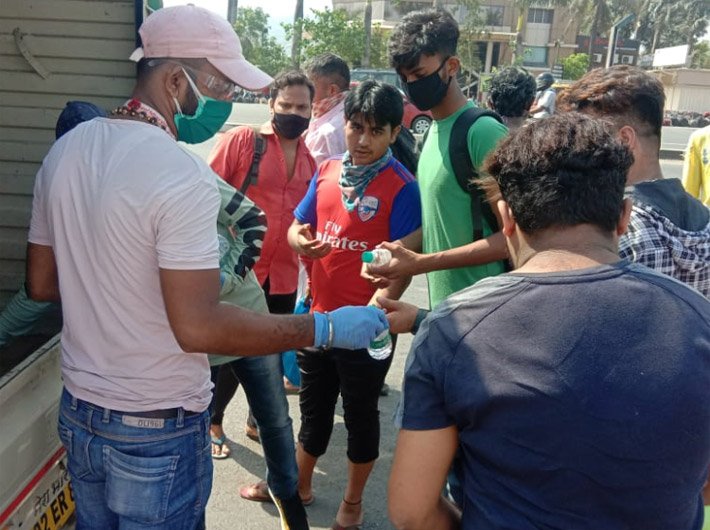 A jeevan rath volunteer distributes food and water to migrant labourers on move (Photo Courtesy: Jeevan Rath initiative)