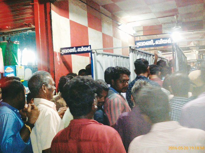 People queue up before a government-run liquor shop in Thrissur, a day before a strike.